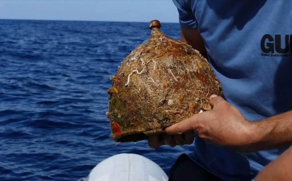Investigador sosteniendo el casco romano montefortino de bronce justo después de su recuperación